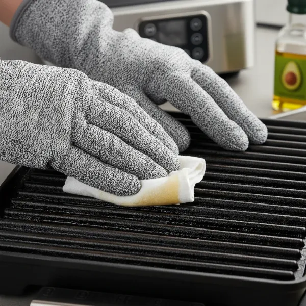 Hands using a cloth to apply a thin layer of cooking oil to cast iron grill grates